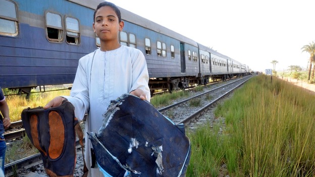 A boy holds school bags recovered from the site of a train crash