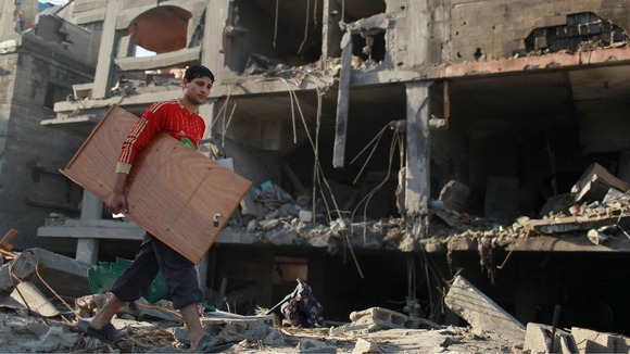 A Palestinian carries his belongings from a destroyed house after an Israeli air strike in the northern Gaza Strip