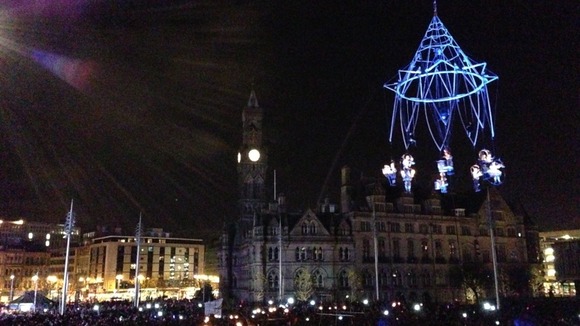 The chandelier of performers is hoisted into the air