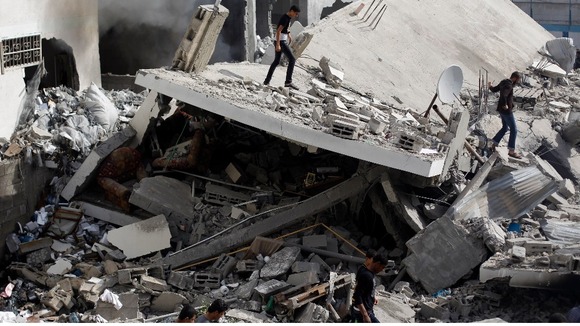 Palestinians walk amongst the rubble of destroyed house after an Israeli air strike in Gaza City