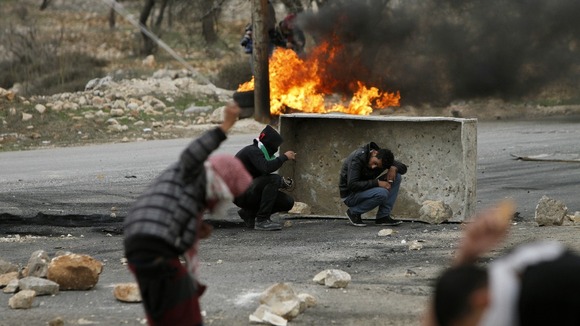 A Palestinian throws a stone using a sling shot at Israeli forces in the West Bank 
