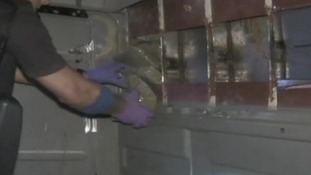 Drugs being removed from a hidden compartment in a lorry
