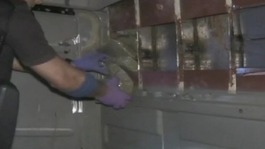 Drugs being removed from a hidden compartment in a lorry