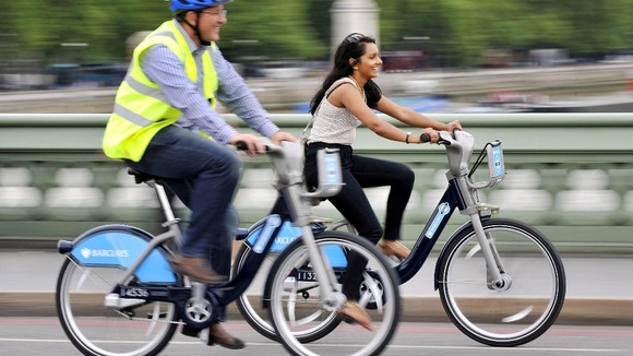 A man and woman ride the cycle hire scheme bikes.