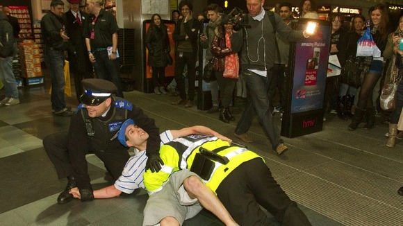 The comic character is restrained by the real Community Support Officer on Oxford Street