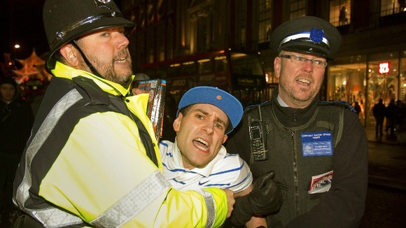 Lee Nelson is restrained by an actor playing a Policeman (on the left) and a real Community Support Officer