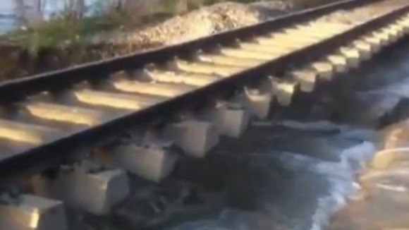 The flood waters wash away the ground supporting railway tracks near Axeminster