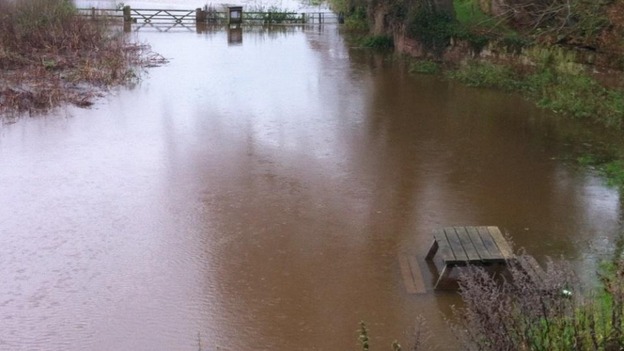 A half submerged picnic table next to the River Dee