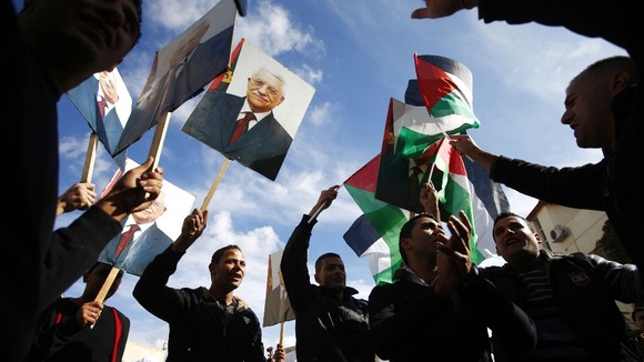 Palestinians in Ramallah hold placards depicting President Abbas during a rally in support of Abbas' efforts at the UN