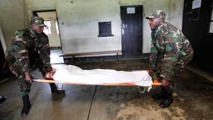 Rwanda army officers carry a wounded FDLR rebel fighter
