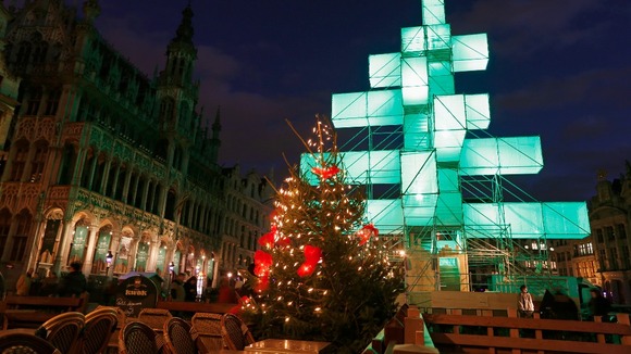 A traditional Christmas tree stands at the foot of the illuminated steel installation at Brussels' Grand Place
