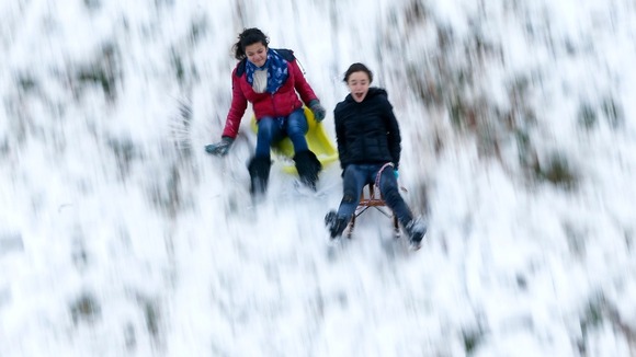 Children ride sledges down an hill as the first snowfall of the season hits Brussels.