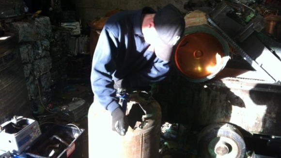 Workers dismantling a copper boiler at a scrap metal dealership in Derbyshire