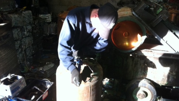 Workers dismantling a copper boiler at a scrap metal dealership in Derbyshire