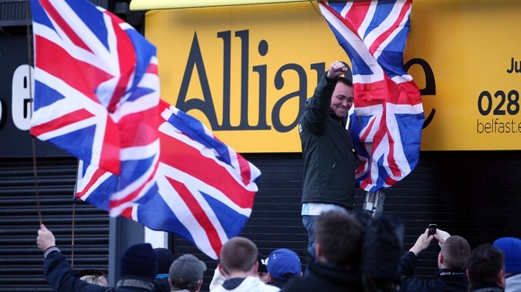 Campaigners hand a Union flag from the office of an Alliance MP