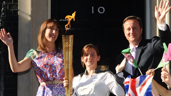 Samantha Cameron and David Cameron stand either side of Olympic Torch bearer Kate Nesbitt in their Christmas card.