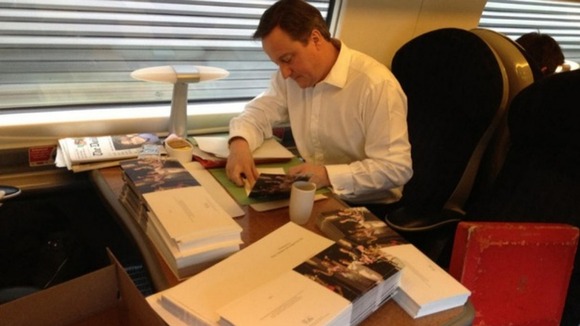 Cameron's team has posted a picture on Twitter of the PM sitting on the train signing the cards: "A lengthy task!" he says.
