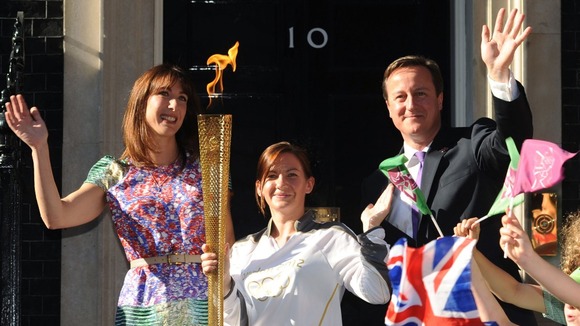 Samantha Cameron and David Cameron stand either side of Olympic Torch bearer Kate Nesbitt in their Christmas card.