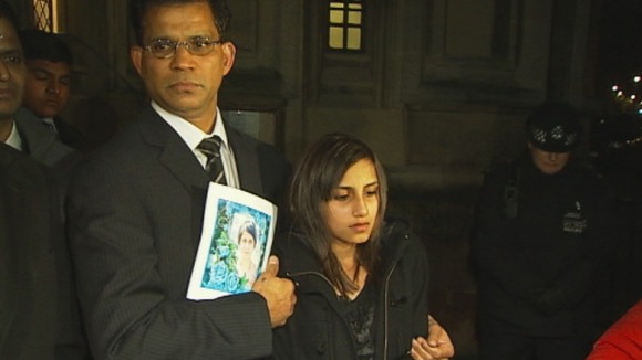 Benedict Barboza holds a picture of his wife, Jacintha Saldanha, and stands with their daughter outside the House of Commons