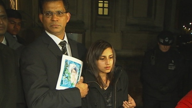 Benedict Barboza holds a picture of his wife, Jacintha Saldanha, and stands with their daughter outside the House of Commons