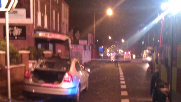 The petrol-bombed car is pictured and surrounded by police personnel in Belfast.