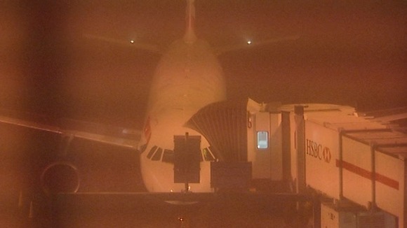 A plane seen through the fog blanketing Heathrow Airport