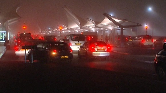 Cars wait in the fog to drop off passengers