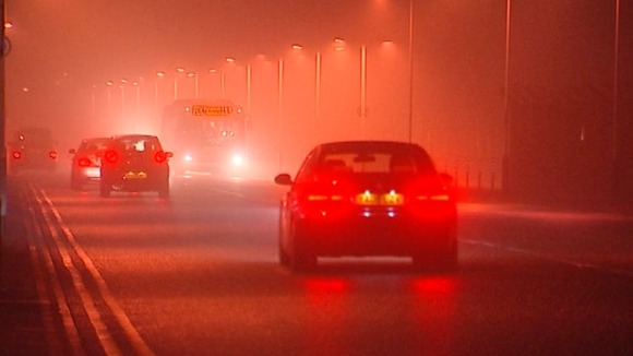 Cars and buses make their way through the fog around Heathrow Airport