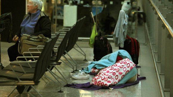 Passengers sleep as they prepare to depart from Terminal 5 at Heathrow Airport