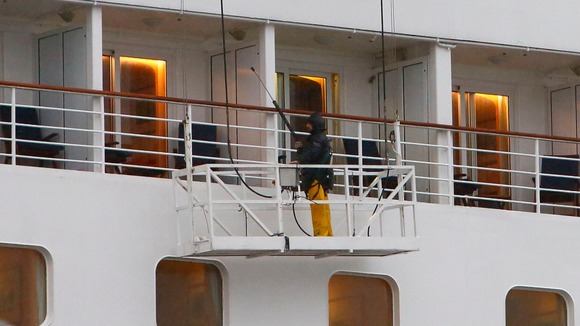 A worker a jet wash to clean the outside of the cruise liner Oriana