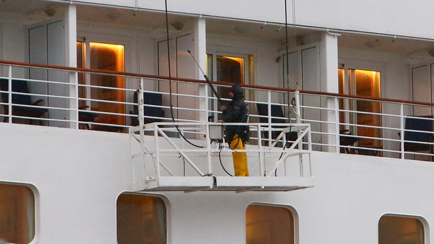 A worker a jet wash to clean the outside of the cruise liner Oriana