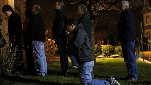 People stand outside a vigil at the Saint Rose of Lima church in Newtown, Connecticut