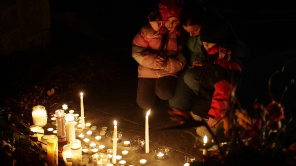 A family prays as they kneel over a makeshift memorial