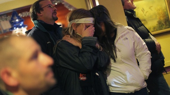 A woman covers her face as she watches President Obama speak on a television in Newtown, Connecticut