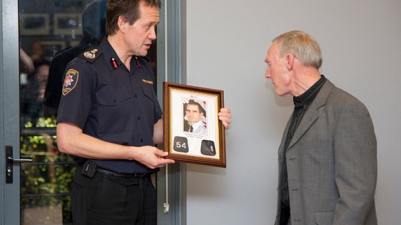 Chief Officer John Bonney presents James Shears's station number lapels to James's father Ed