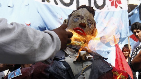 A man sets fire to an effigy depicting Prince William during a demonstration outside the British embassy in Buenos Aires.