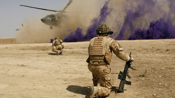 British soldiers cover themselves from dust as a helicopter lands at the Malgeer village in Helmand province