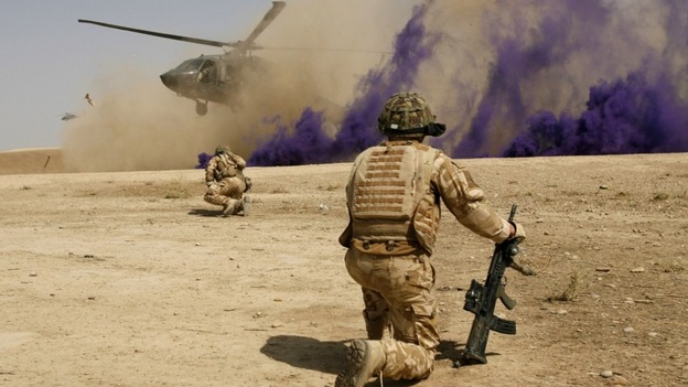 British soldiers cover themselves from dust as a helicopter lands at the Malgeer village in Helmand province