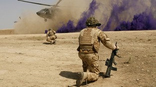 British soldiers cover themselves from dust as a helicopter lands at the Malgeer village in Helmand province