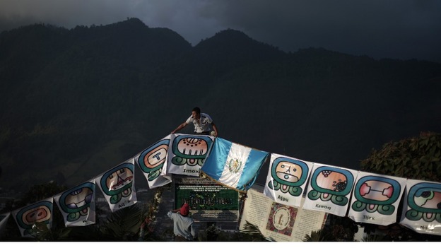 Man arranges pre-Hispanic symbols and Guatemalan flag ahead of a special ceremony