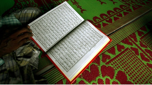 A man pictured reading the Koran