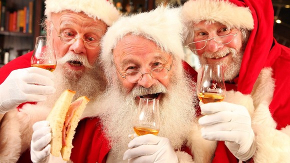 A group of Santas enjoy a dram of whisky and a bacon sandwich.