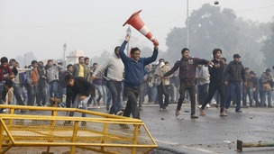Demonstrators run and throw stones towards the police during a protest in front of India Gate in New Delhi