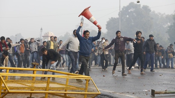 Demonstrators run and throw stones towards the police during a protest in front of India Gate in New Delhi