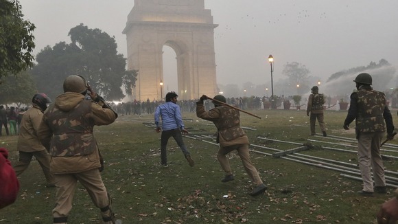 Policeman uses a baton to disperse a demonstrator during a protest in front of India Gate in New Delhi
