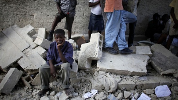 A boy sits next to the remains of a destroyed school after an earthquake in Haiti in 2010
