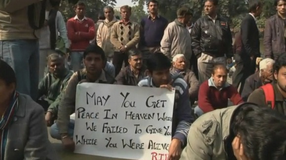 Protesters hold a sign saying 'May you get peace in heaven which we failed to give you while you were alive, R.I.P.'
