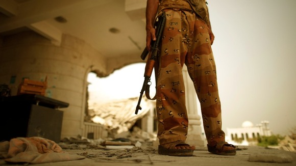 An army soldier stands guard outside a damaged government building in Zinjibar.