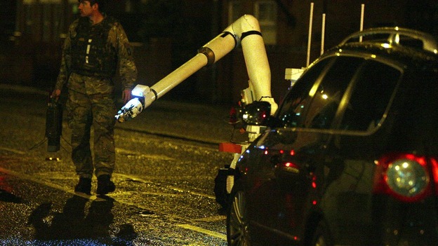An army bomb disposal expert and robot moves in to examine the scene