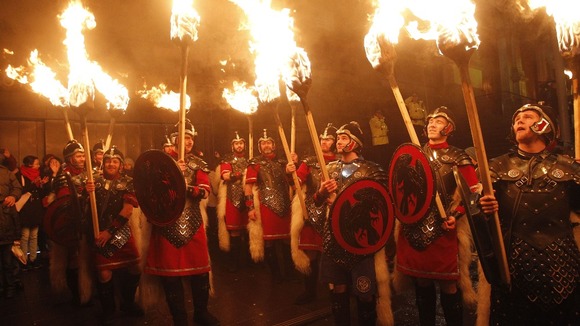 Torchbearers are being led by massed pipes and drums and the Up Helly Aa' Vikings from Shetland in a procession through Edinburgh.